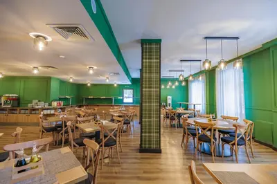 a restaurant with wooden tables and chairs and green walls at Iglika Hotel & Villas Borovets in Borovets