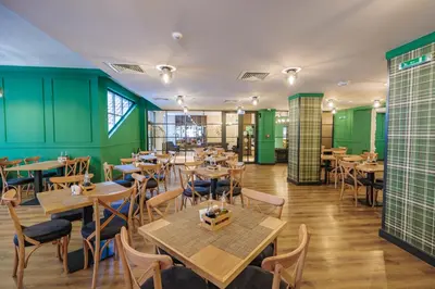 a restaurant with tables and chairs and green walls at Iglika Hotel & Villas Borovets in Borovets