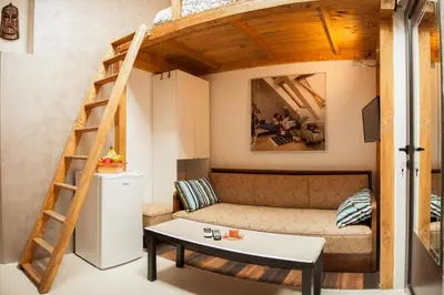 a living room with a couch and a ladder at Vitosha Blvd - Attic Studio in Sofia