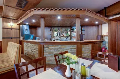 a dining room with a bar and a table at Shiroka Laka Hotel in Shiroka Lŭka