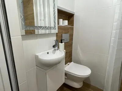 a white bathroom with a toilet and a sink at Top center 
