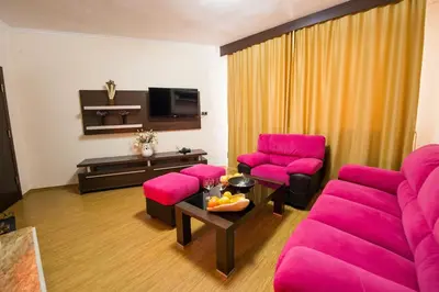a living room with pink chairs and a tv at Family Hotel Hebar in Batak
