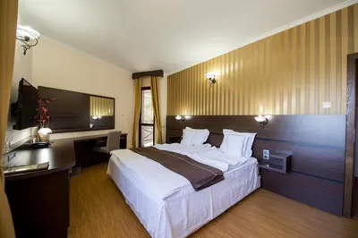 a bedroom with a large bed and a desk at Family Hotel Hebar in Batak