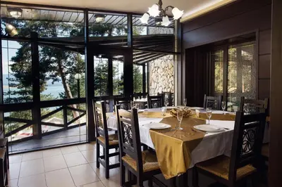 a dining room with a table and a large window at Family Hotel Hebar in Batak