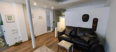 a living room with a black leather couch and wooden floors at Cozy Flat in Sofia