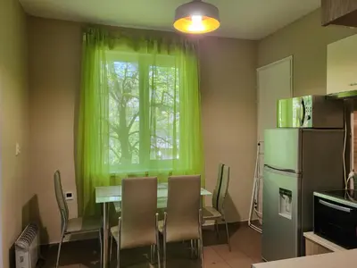 a kitchen with a table and a window with green curtains at Cozy apartment in the heart of Sofia in Sofia