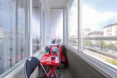 a red table and chairs in a room with windows at Visit Sofia Macedonia Square Central Apartment by Flat Mаnager in Sofia