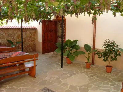 a patio with potted plants and a wooden bench at Centaur Family Hotel in Rila