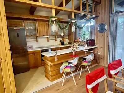 a kitchen with a counter with chairs and a refrigerator at Pirin Golf Villa Emila in Bansko