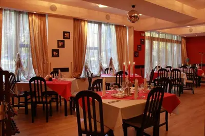 a dining room with tables and chairs with red tablecloths at Hotel Real in Plovdiv