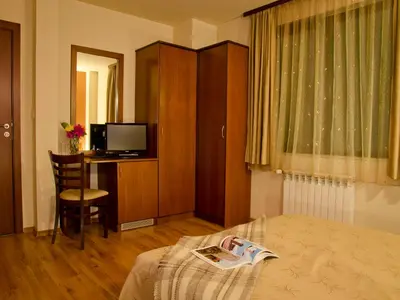 a bedroom with a bed and a desk and a television at Bizev Hotel in Bansko