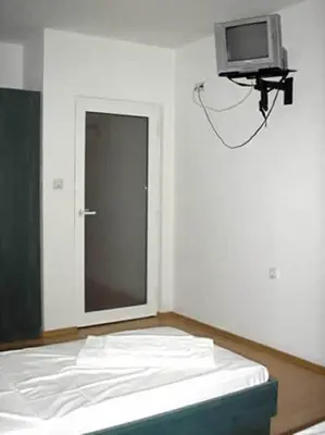 a room with a bed and a tv on the wall at Hotel Pilevski in Blagoevgrad