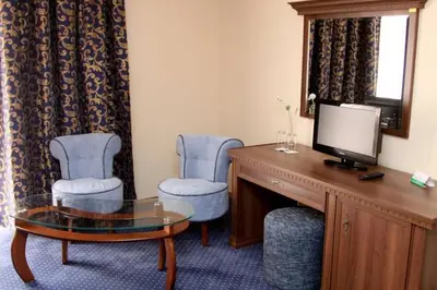 a room with two chairs and a desk with a television at Hotel Park Bachinovo in Blagoevgrad
