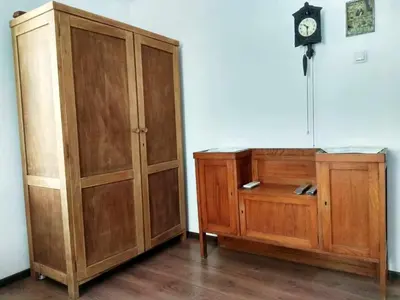 a wooden cabinet and a clock on a wall at Ayki - historic centre apartment in Sofia