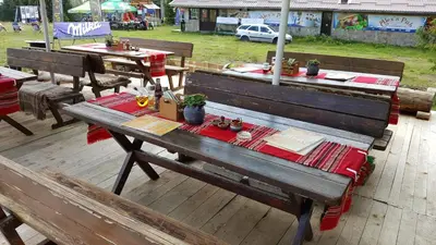 a wooden bench with a table with a red table cloth at Papa Moose Pamporovo in Pamporovo