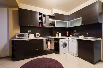 a kitchen with black cabinets and a washing machine at City Apartments in Sofia
