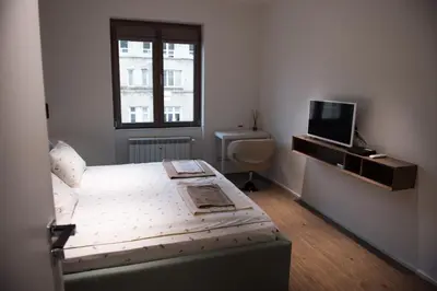a bedroom with a bed and a tv and a window at Apartment Rotonda in Sofia
