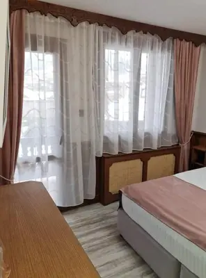 a bedroom with two beds and a window with curtains at Chuchura Family Hotel in Koprivshtitsa