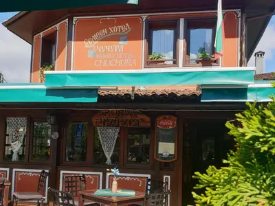 a building with a table and chairs in front of it at Chuchura Family Hotel in Koprivshtitsa