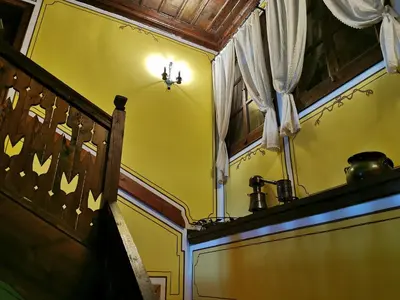 a room with a yellow wall and a window at Hadji Neikovi Guest Houses in Koprivshtitsa