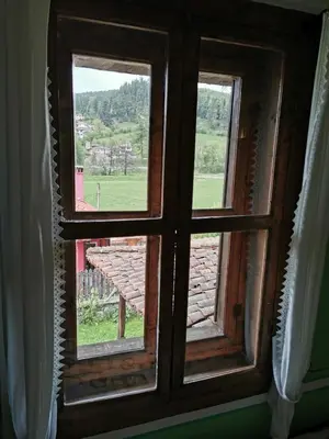 an open window with a view of a field at Hadji Neikovi Guest Houses in Koprivshtitsa