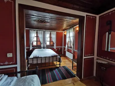 a bedroom with a bed in a room with red walls at Hadji Neikovi Guest Houses in Koprivshtitsa