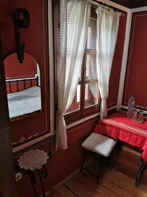 a bedroom with a mirror and a table and a window at Hadji Neikovi Guest Houses in Koprivshtitsa