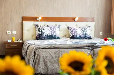 a bedroom with a bed with blue and purple pillows at Family Hotel Romantika in Velingrad