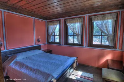a bedroom with a bed and two windows at Gozbarov's Guest House in Koprivshtitsa