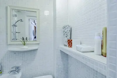 a white tiled bathroom with a sink and a mirror at Shik & Chic One Bedroom Central Apartment Graf Ignatiev x Shishman Corner by Flat Mаnager in Sofia