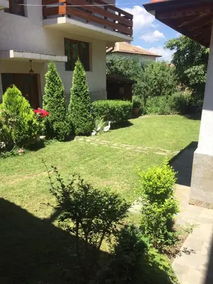 a yard with bushes and trees and a house at Guest Rooms Vachin in Bansko