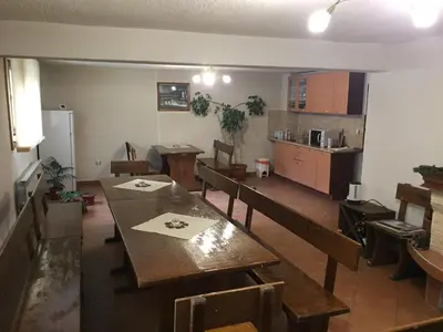 a dining room with tables and chairs and a kitchen at Guest Rooms Vachin in Bansko