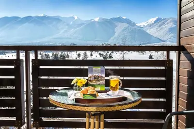 a table on a balcony with a glass of beer at Terra Hotel in Bansko