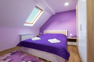 a purple bedroom with a bed and a window at Serdika Round Tower Apartments in Sofia