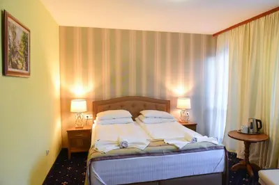 a bed in a hotel room with two lamps at Family Hotel Lazur in Bansko