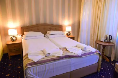 a bedroom with a bed with white sheets and pillows at Family Hotel Lazur in Bansko