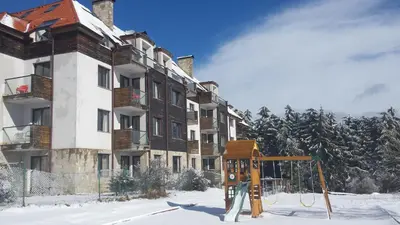 a apartment building with a playground in the snow at Chamkoria Chalets in Borovets