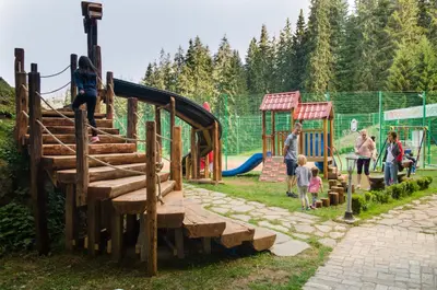 a group of people walking around a playground at Complex Kamelia in Pamporovo