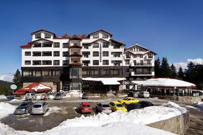 a large building with cars parked in a parking lot at Snezhanka Apartments TMF in Pamporovo