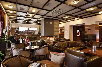 a restaurant with leather chairs and tables and a bar at Snezhanka Apartments TMF in Pamporovo