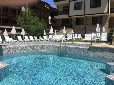 a swimming pool with chairs and a building at Maria-Antoaneta Residence in Bansko
