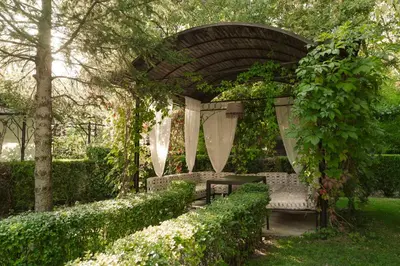a gazebo with a bench in a garden at Family Hotel Edia-Sandanski in Sandanski