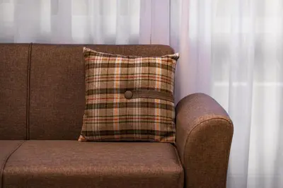 a brown couch with a plaid pillow on it at Family Hotel Edia-Sandanski in Sandanski
