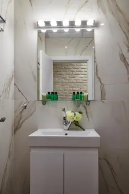 a white bathroom with a sink and a mirror at City Center Studio in Plovdiv