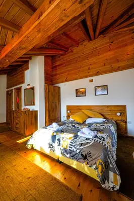 a large bed in a room with wooden ceilings at Guest House Dzhangal in Bansko