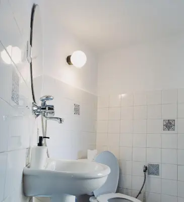 a white bathroom with a sink and a toilet at Dedo Pene Inn in Bansko