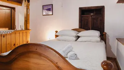 a bedroom with a bed with white sheets and pillows at Dedo Pene Inn in Bansko