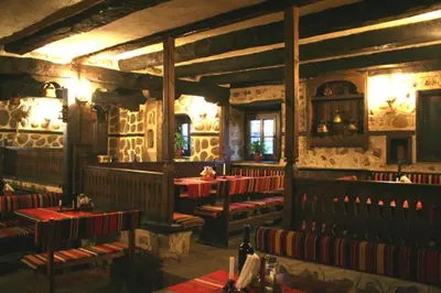 a restaurant with red tables and benches in a room at Guest House Valevicata in Bansko