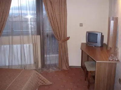 a room with a tv on a wooden desk with a window at Guest House Valevicata in Bansko