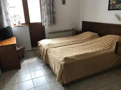 a hotel room with two beds and a television at Durchova Kashta Family Hotel in Bansko